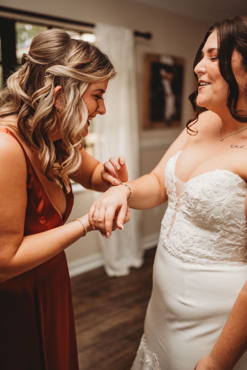 Two people share an intimate getting ready moment before a wedding as they examine a bracelet or jewelry piece.