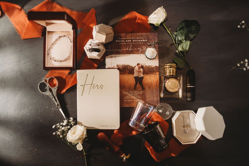 Wedding invitations and decorative elements arranged with orange accents and floral details on dark surface.