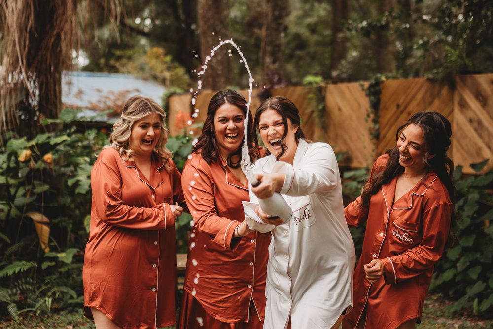 A celebratory moment among friends wearing matching orange attire in an outdoor garden setting.