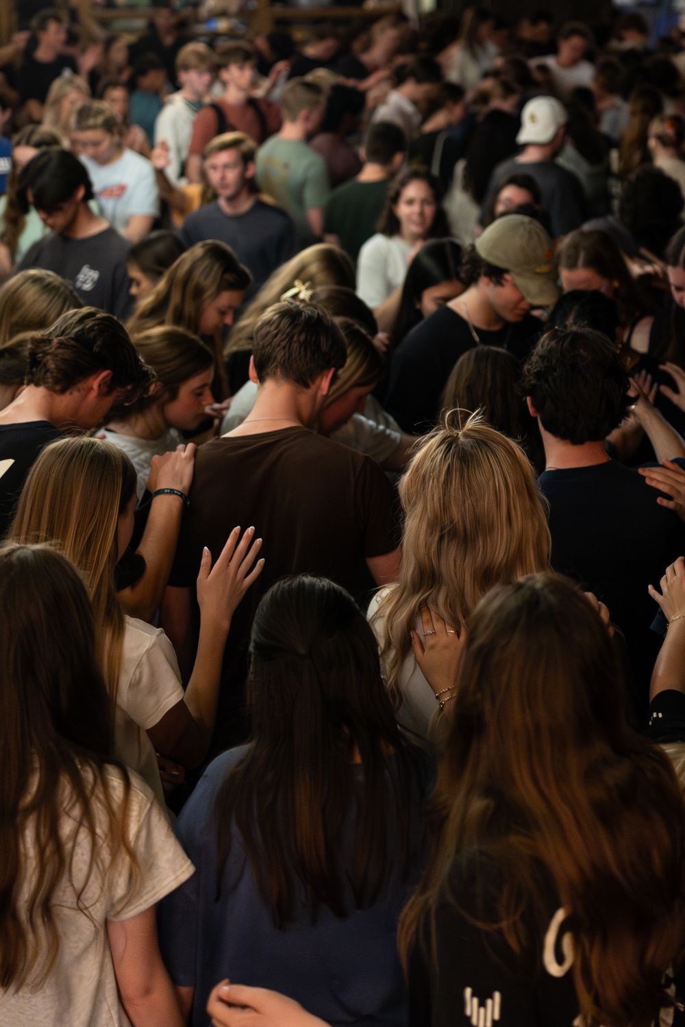 A large crowd of young people gathered together in prayer at a Christian worship event.