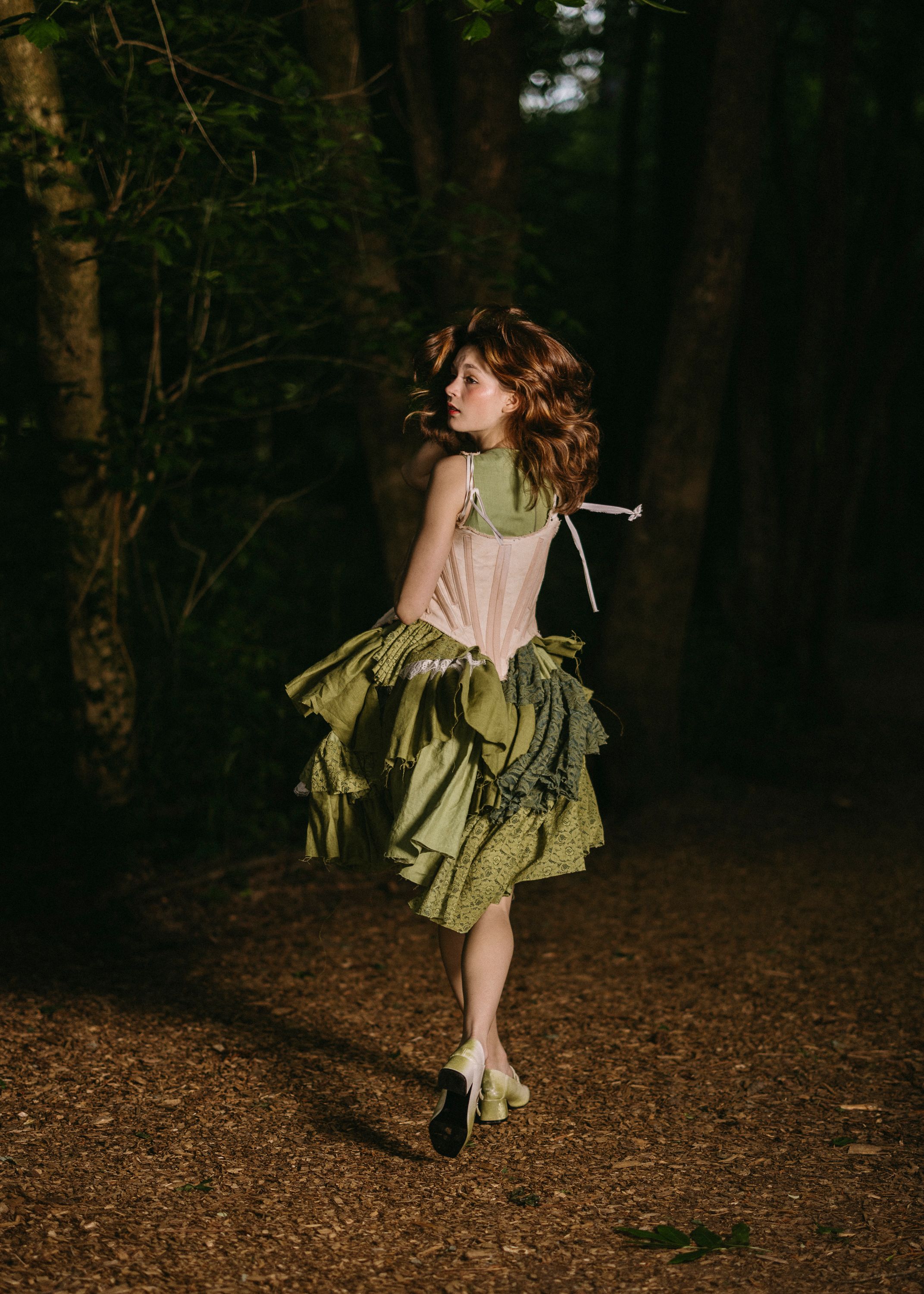 Model running away and looking back in a dim forest