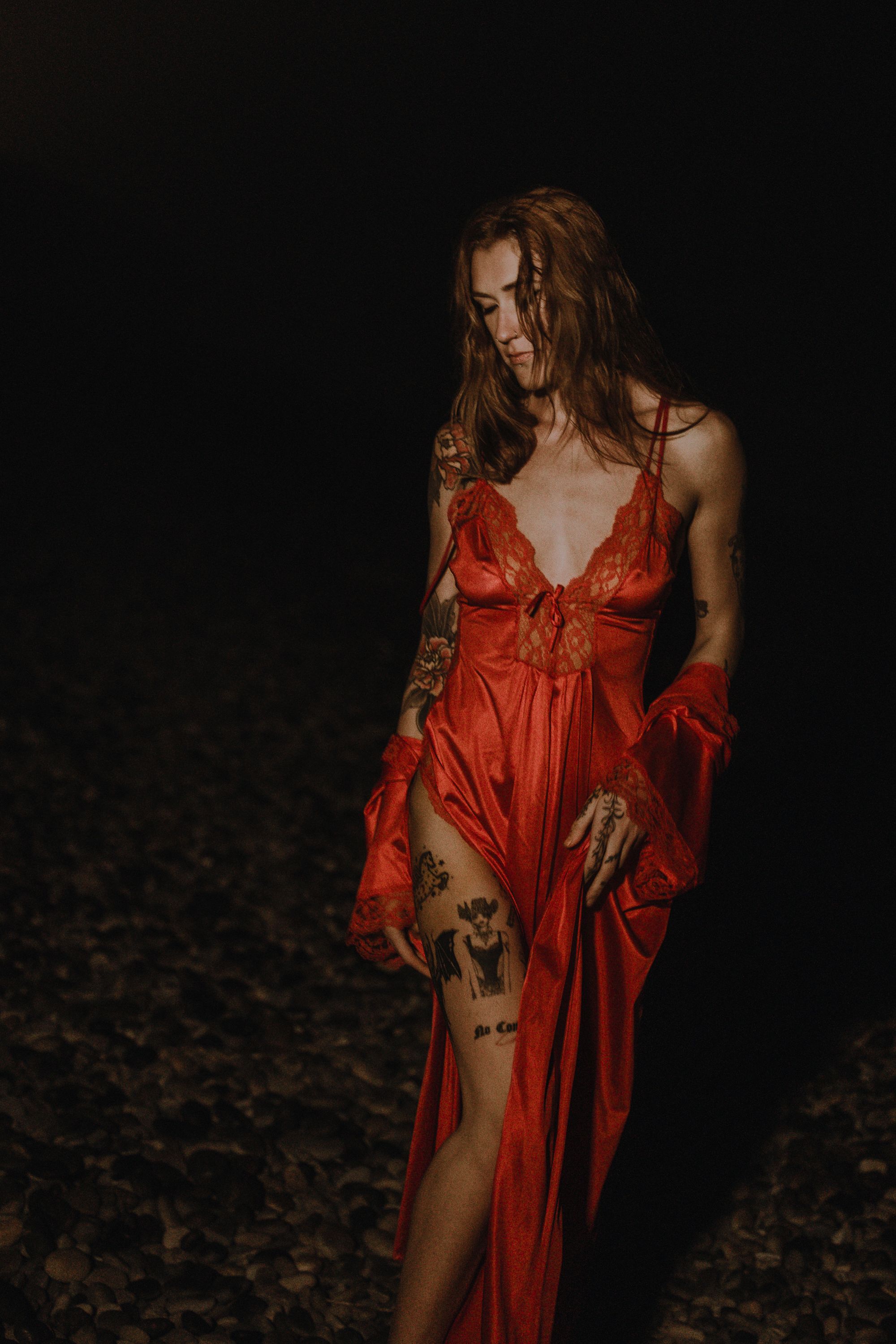 Model posed at night on beach in a red dress
