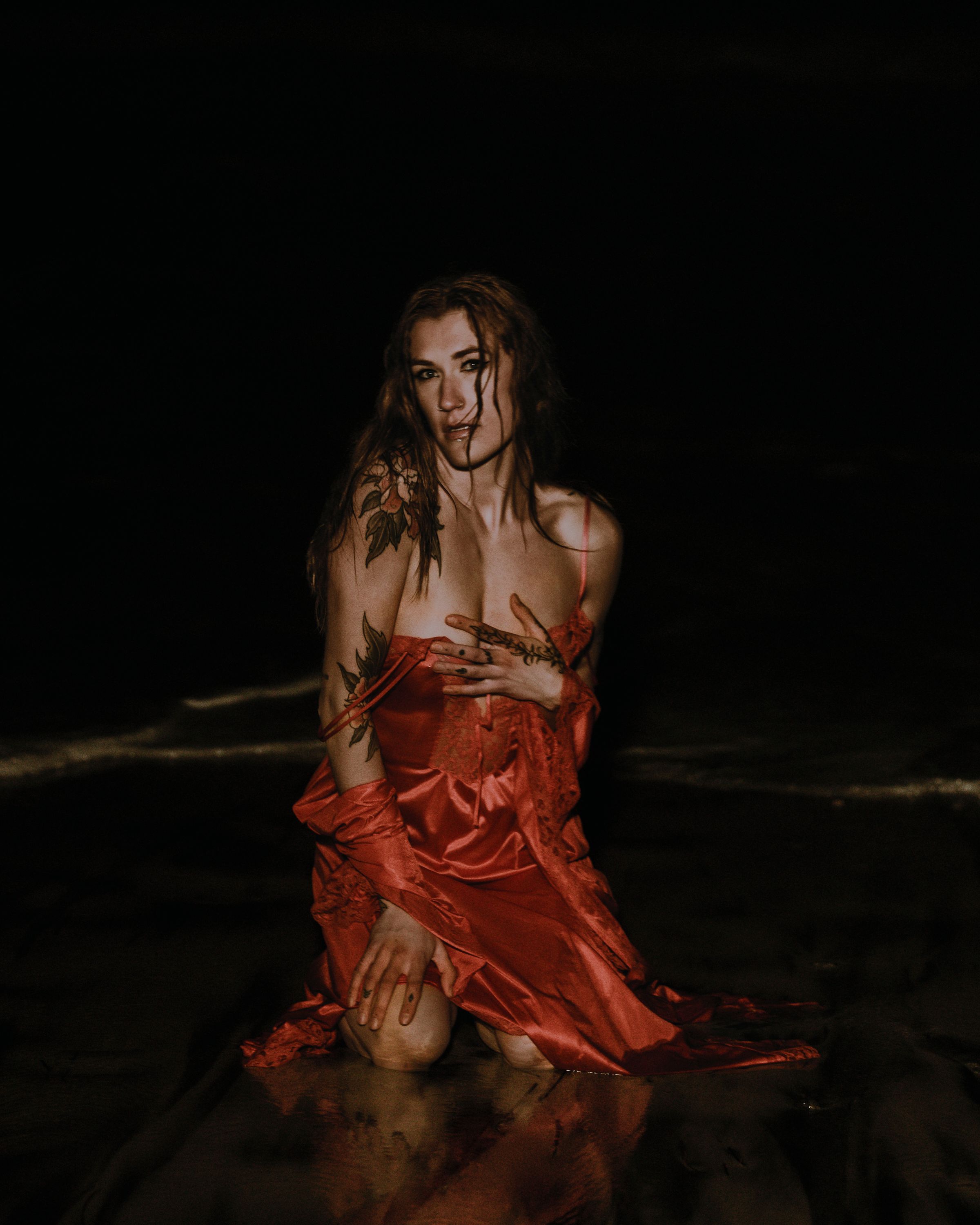 Model posed at night on beach in a red dress