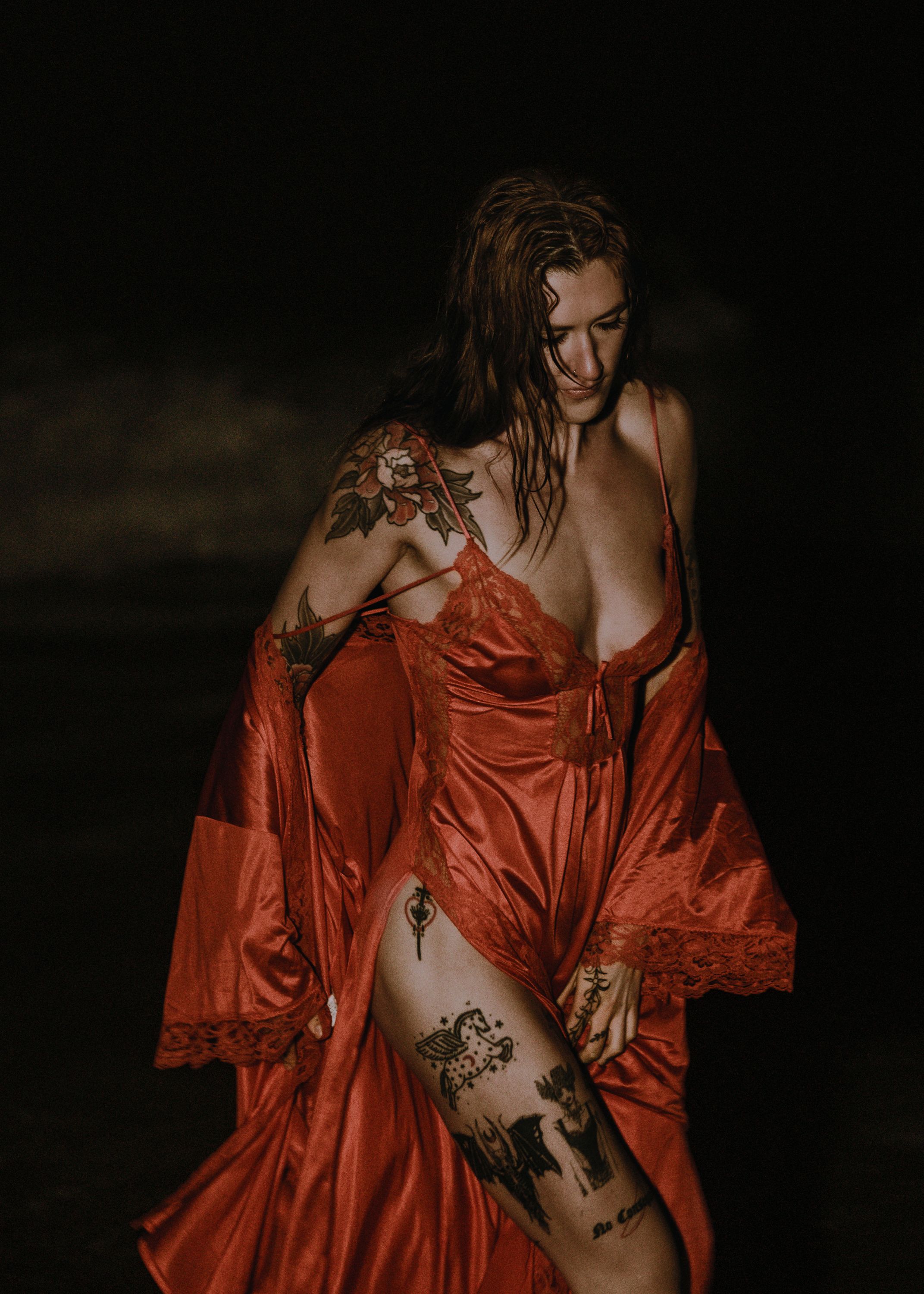 Model posed at night on beach in a red dress