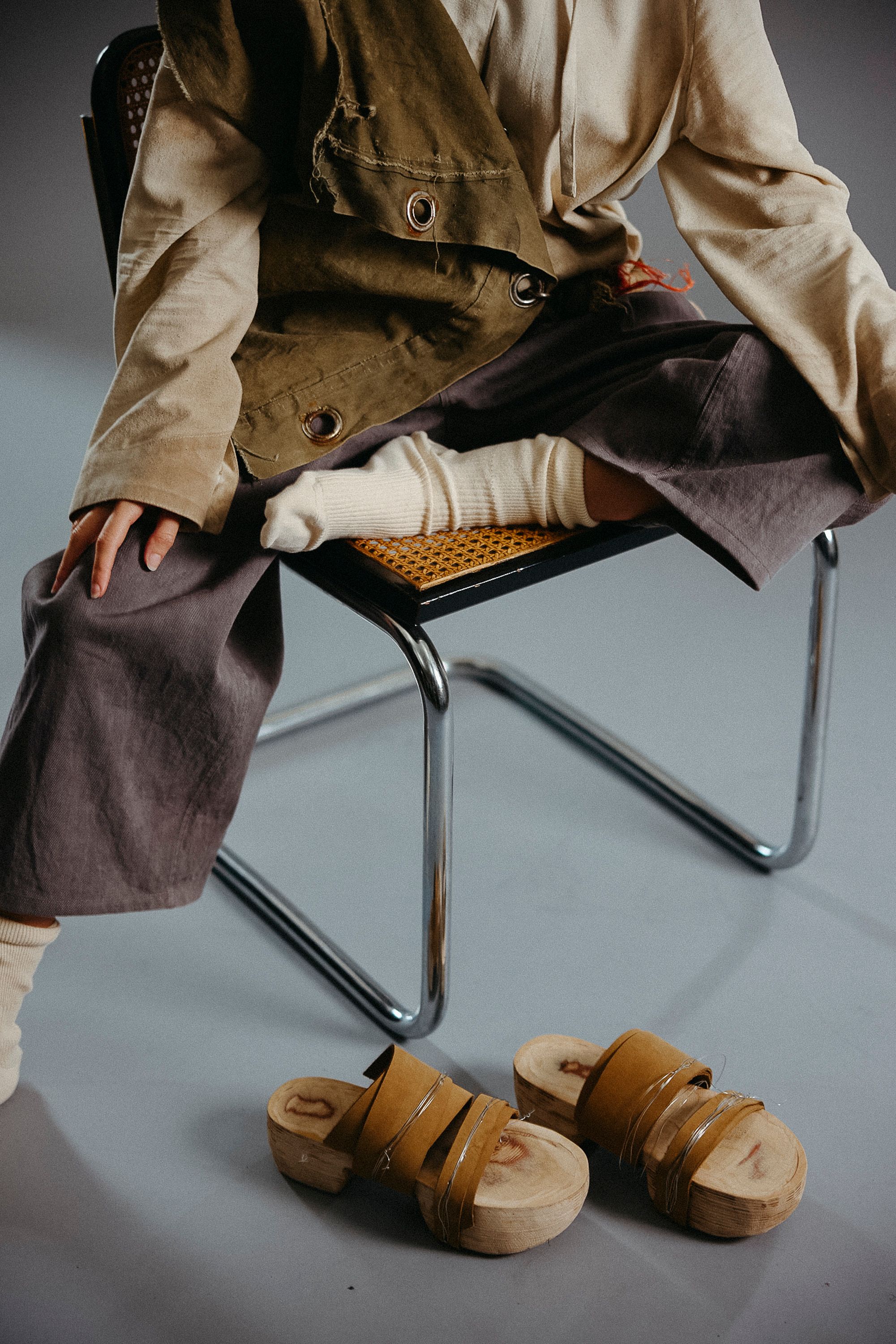 Model sitting on chair with one leg up, shoes below her