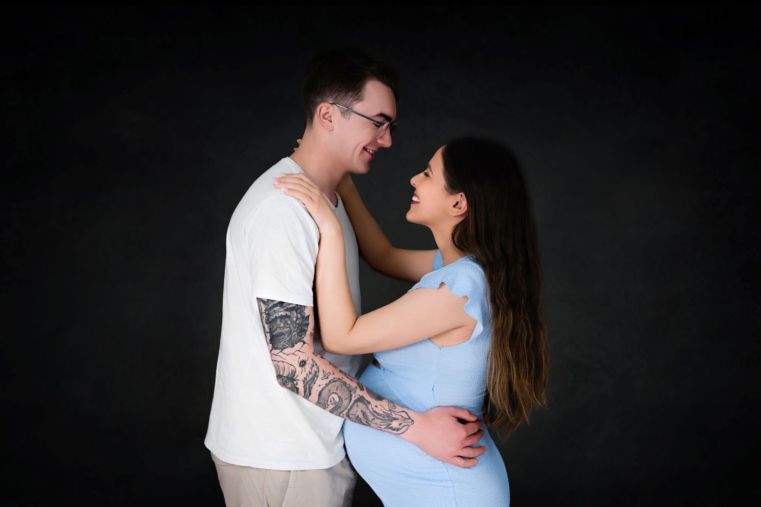 Intimate portrait of a couple embracing against a dark background.