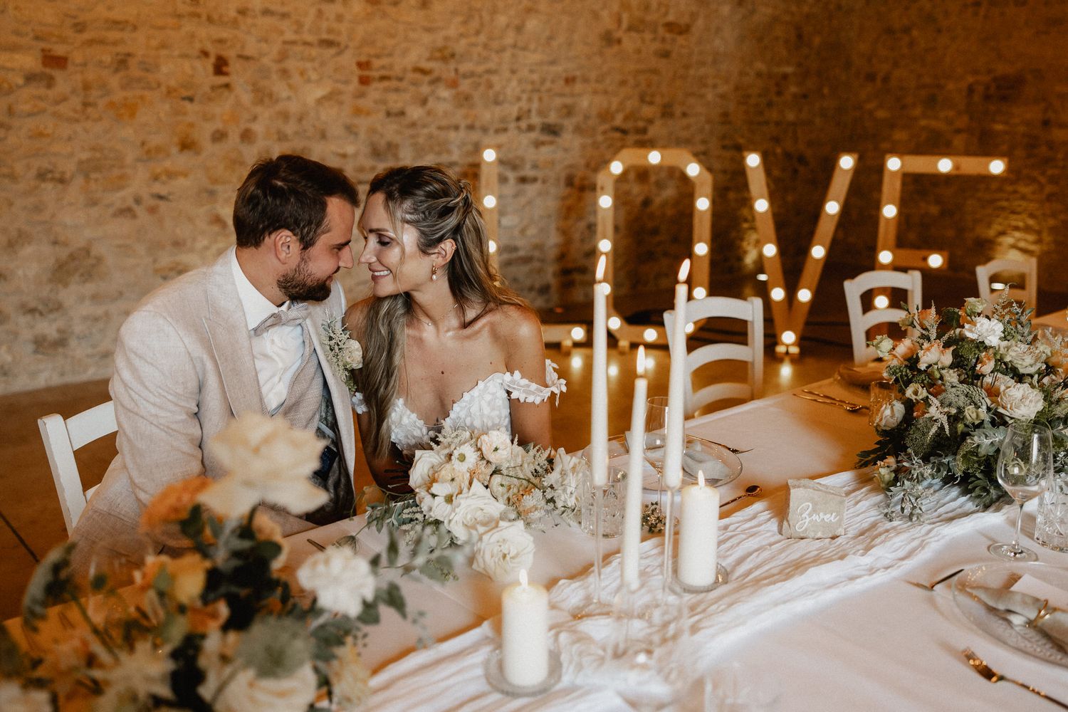 Romantic candlelit wedding reception with LOVE marquee sign and elegant table settings.