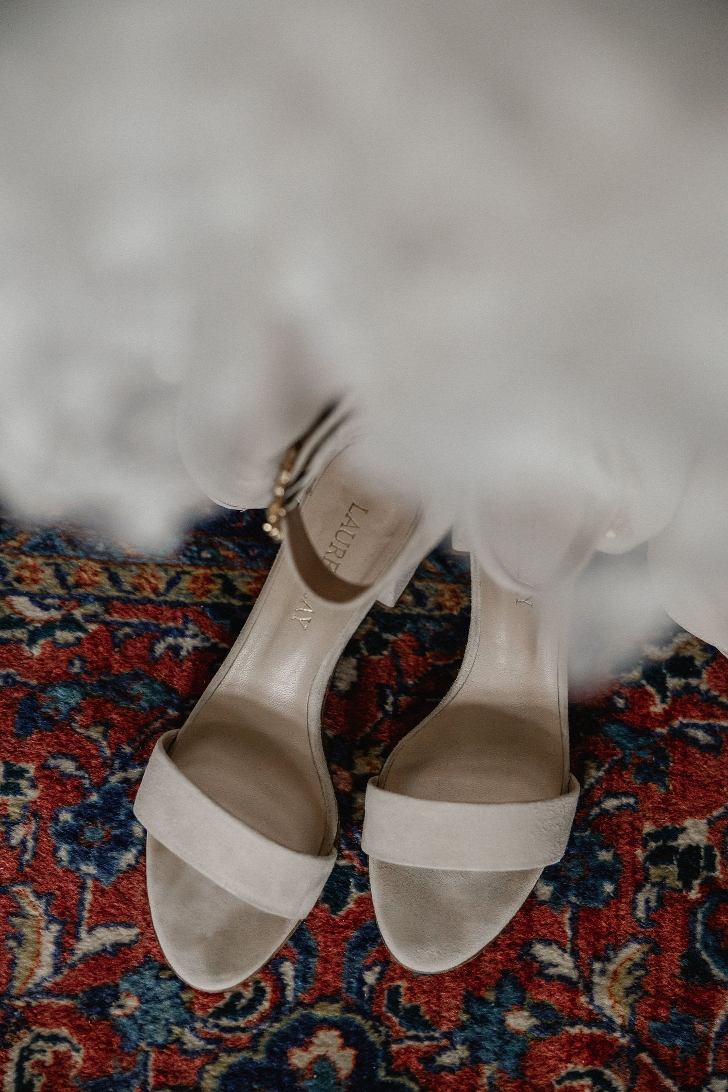 Cream colored bridal sandals on a vintage patterned oriental rug.