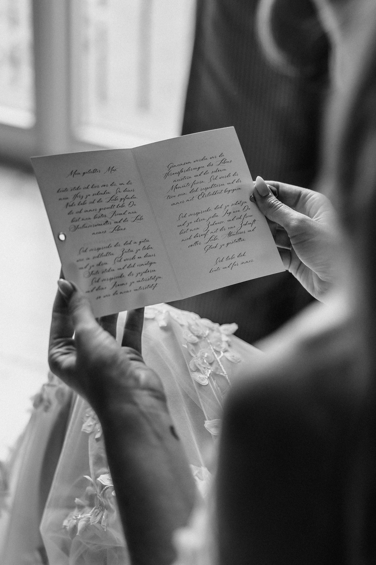 Black and white photo of hands holding handwritten wedding vows or letter.