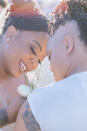An intimate close-up of a couple in white sharing a tender moment outdoors.