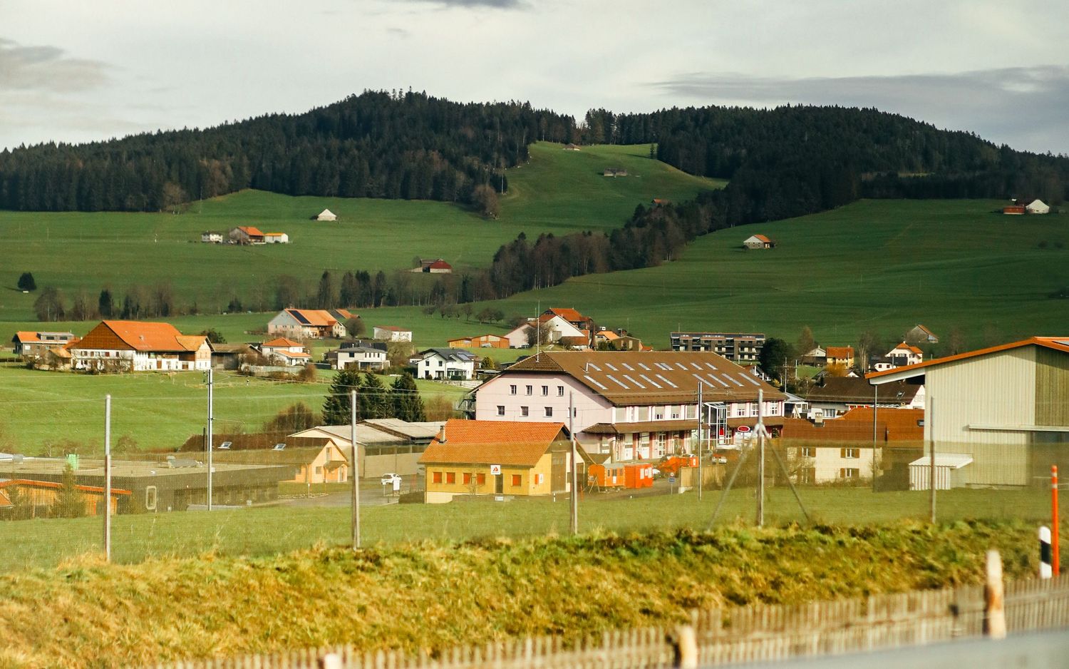 A scenic view of a small European village with colorful houses nestled among green rolling hills.