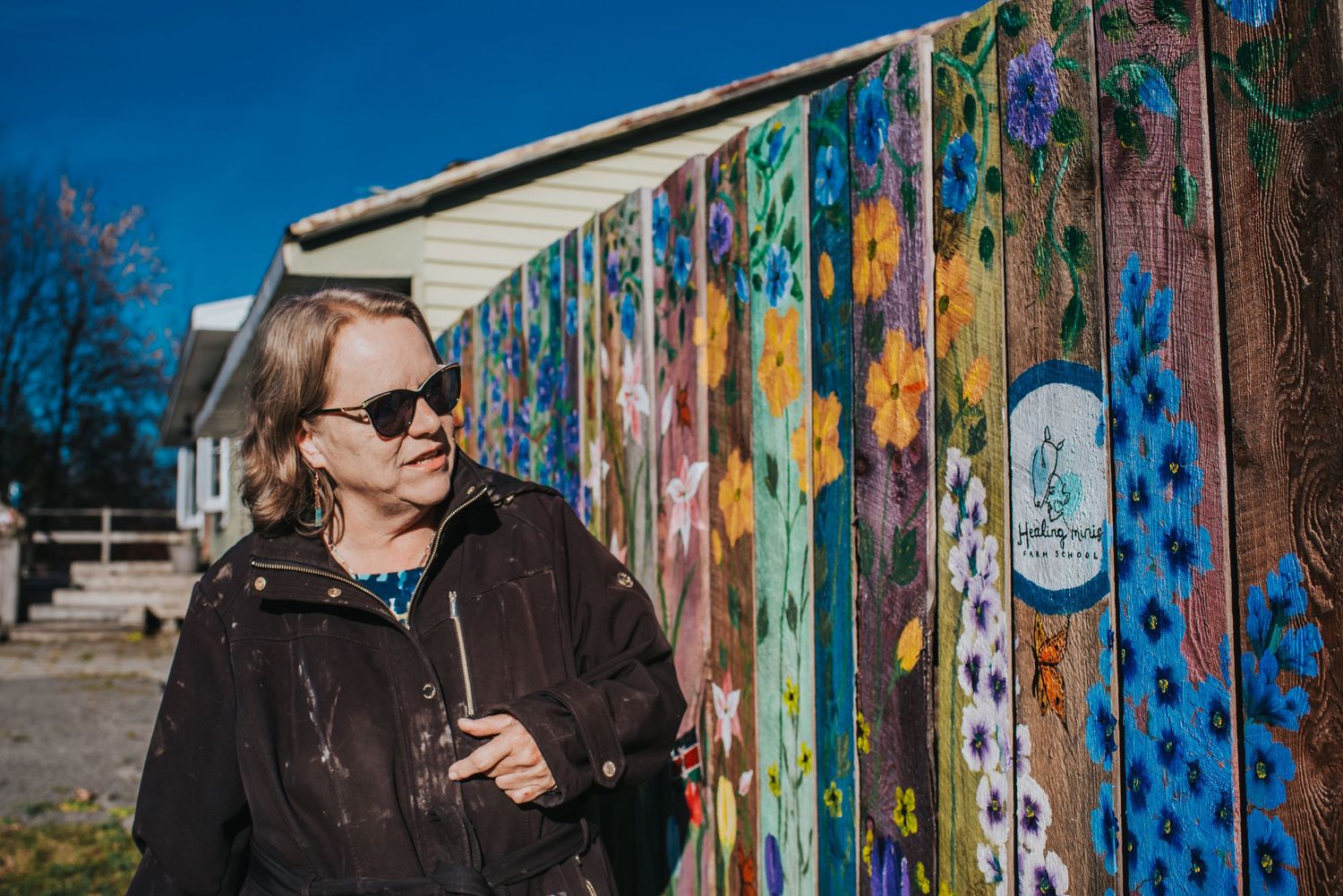 Laurie of Healing Minis Farm School looks at her painted fence as she explains what her charity does.