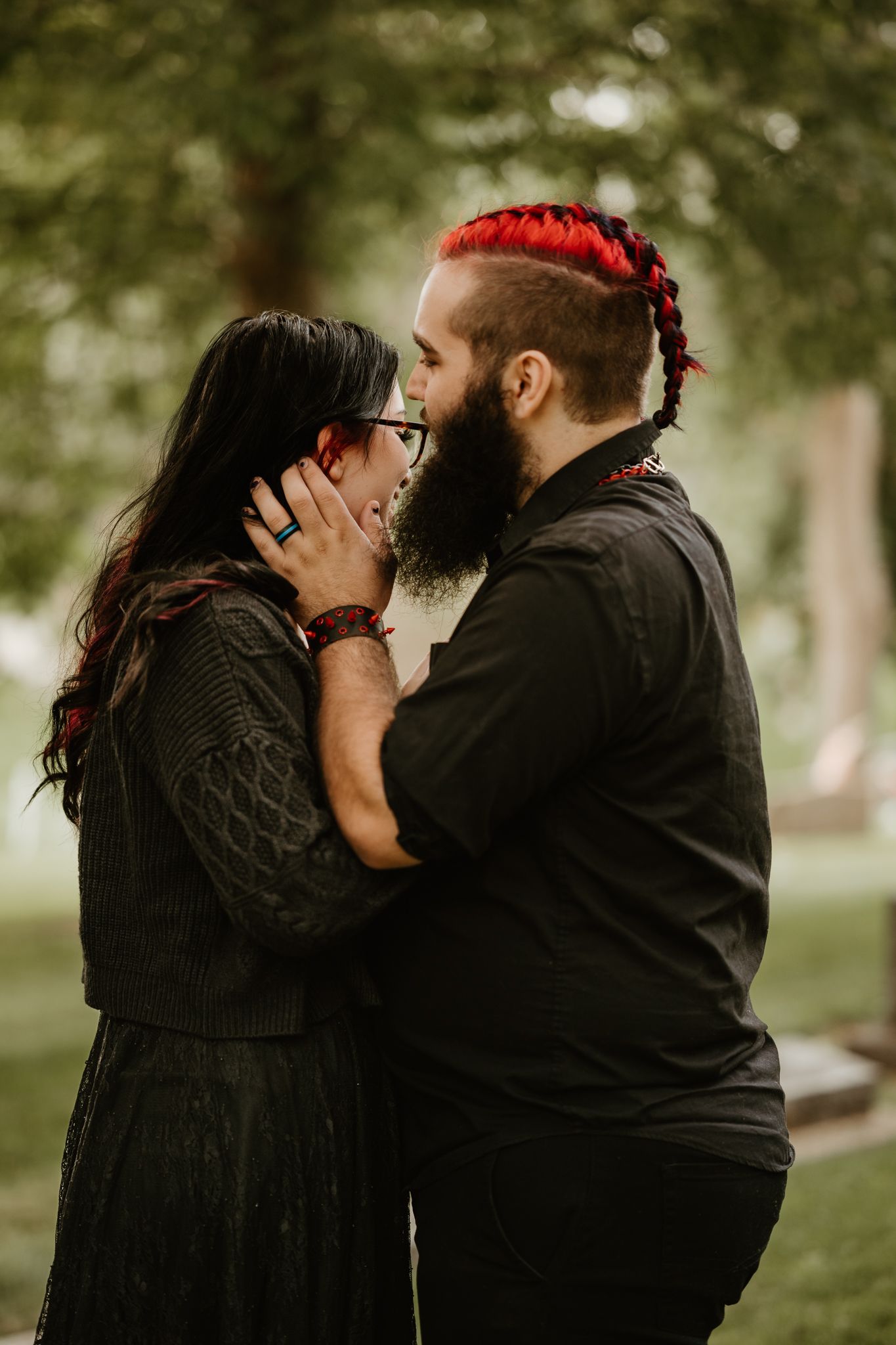 Romantic sequence of a couple in dark clothing sharing tender moments in a park setting.