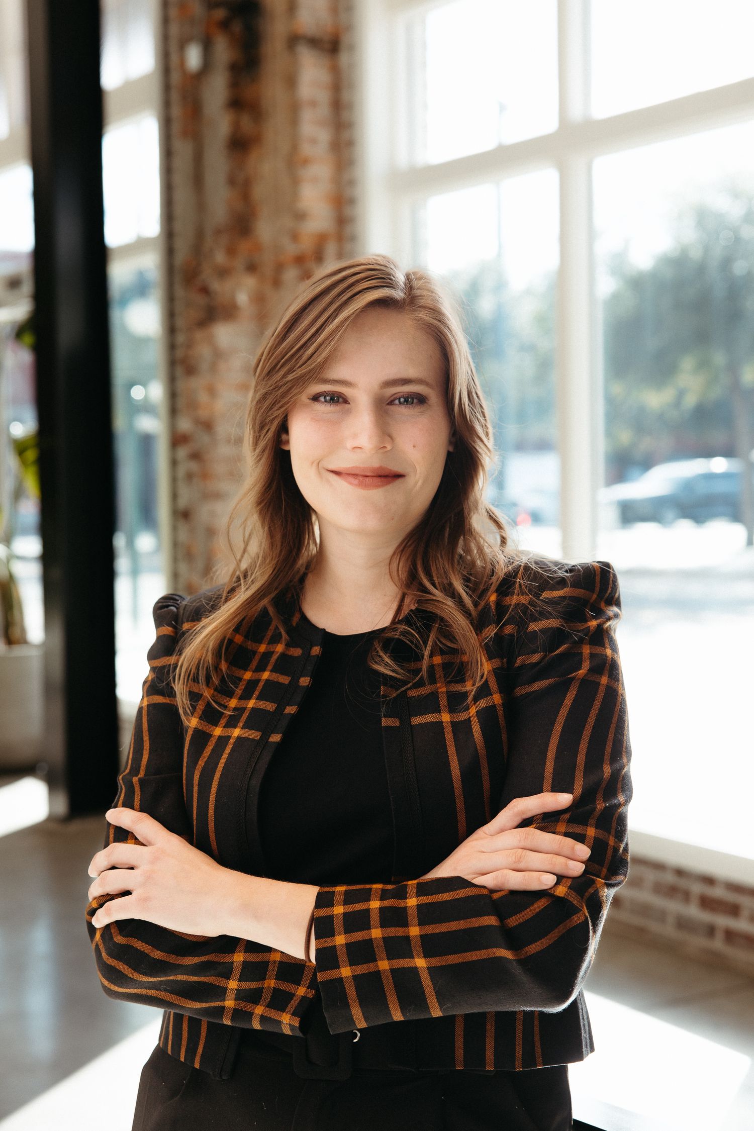 Professional portrait session in bright industrial space with brick walls and large windows.