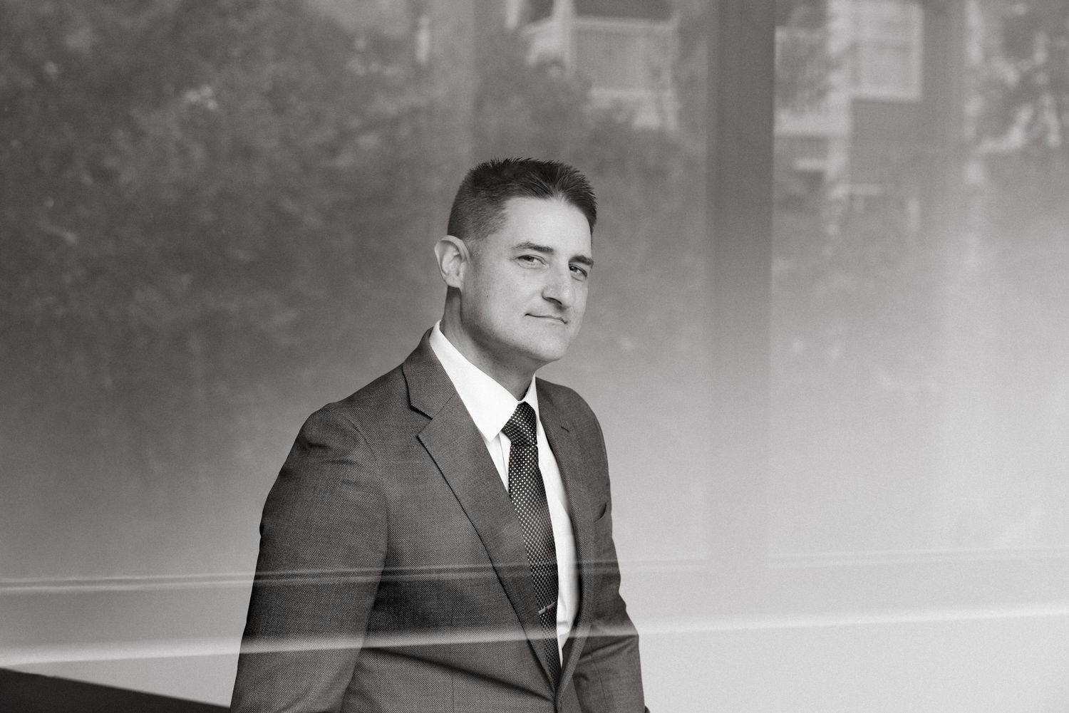 Professional businessman in suit and tie posing confidently in black and white portrait photo.