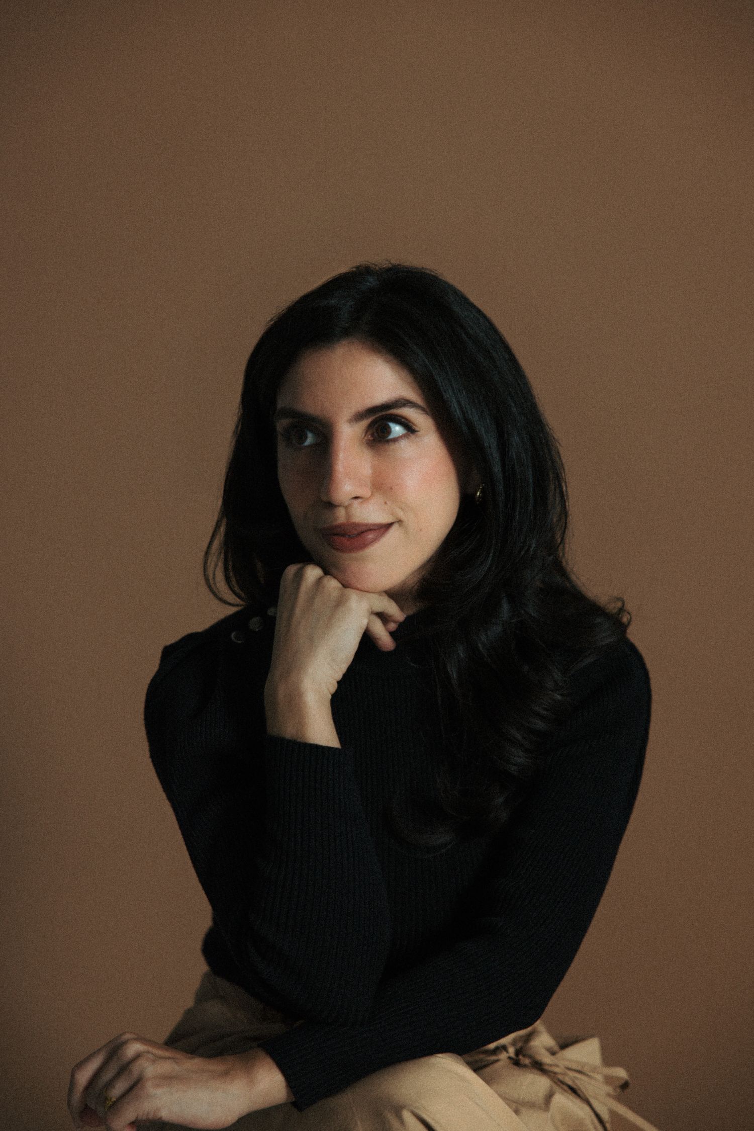 A series of moody portraits showing a person in black clothing against a brown backdrop with dramatic lighting and poses.