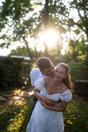 An intimate golden sunset moment captured between a couple in a lush garden setting with soft backlighting.