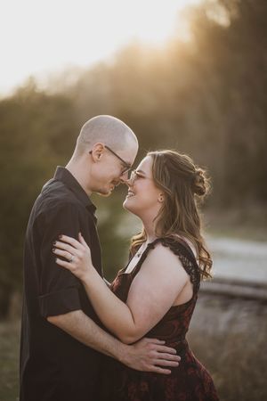 A romantic couple embraces outdoors at sunset with warm golden light in a tender intimate moment.