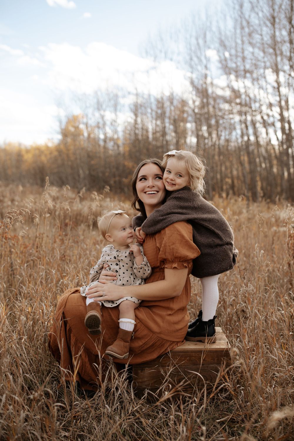 A family sitting together in tall autumn grass during golden hour.