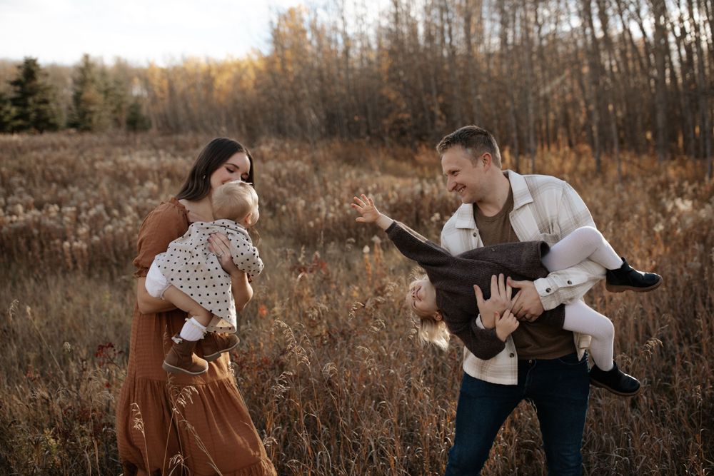 Candid family portraits captured in a rustic field setting during golden hour.
