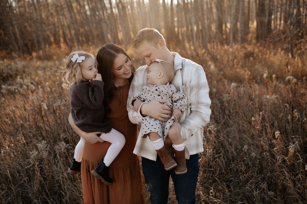 Natural family moments photographed in warm evening light among autumn foliage.