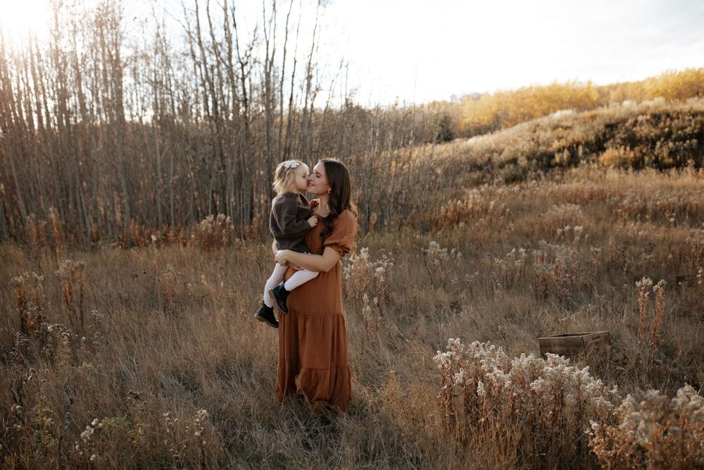 Family portrait session in a golden field with bare trees at sunset.