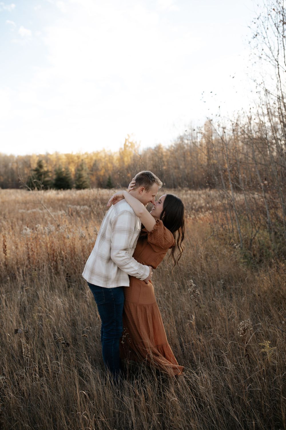Two people share an intimate moment in a golden field at sunset.