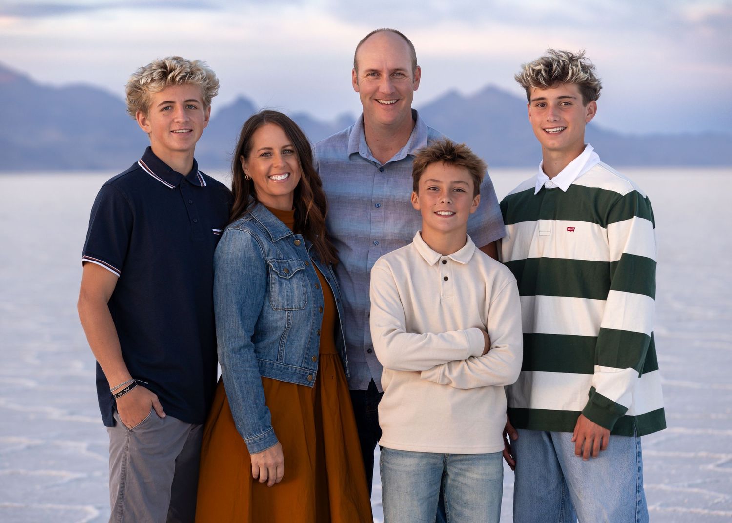 Group of five people posing outdoors against a scenic mountain and water backdrop at the salt flats photography