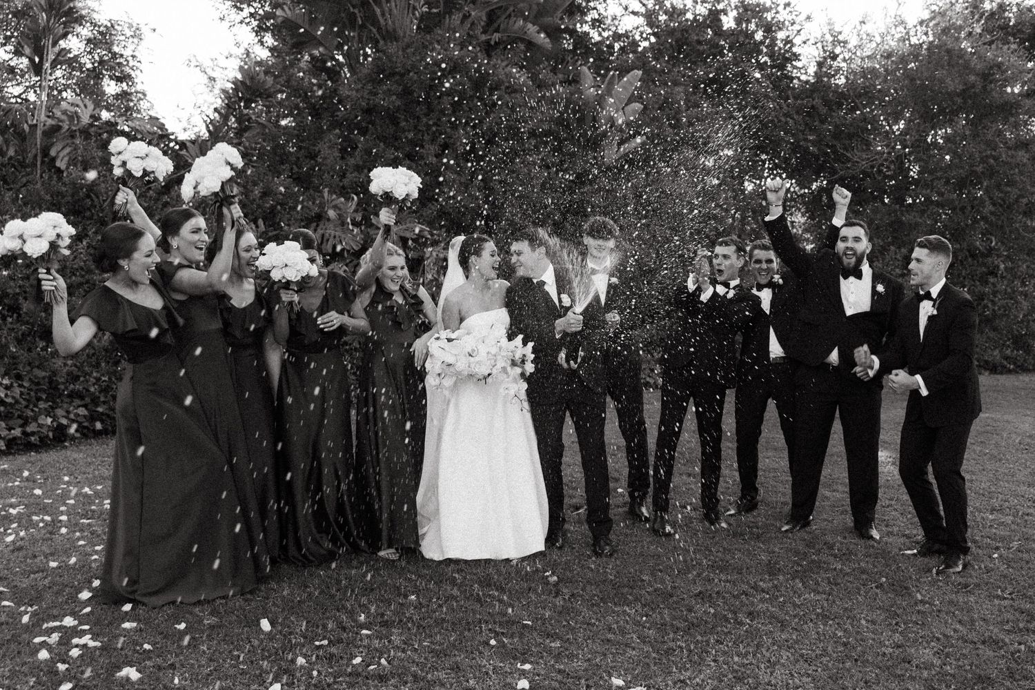 Festive wedding celebration captured in black and white with sparklers and joyful guests.