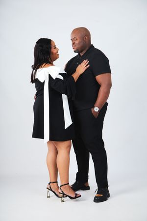 Two people in black outfits strike playful poses against a white backdrop in a series of romantic shots.