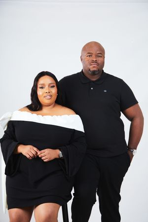 A couple wearing matching black outfits poses together against a white background in a series of studio photos.