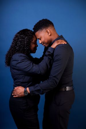 A couple in black formal wear shares intimate poses during a photo shoot.