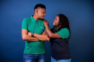A couple wearing green and black poses together in a studio setting.