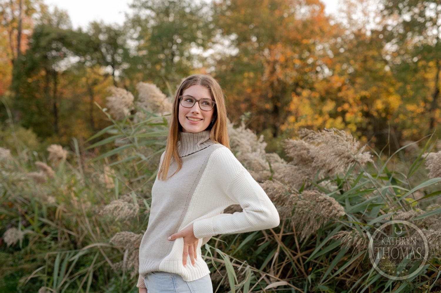Casual autumn portrait featuring someone in a cream sweater posing against fall foliage.
