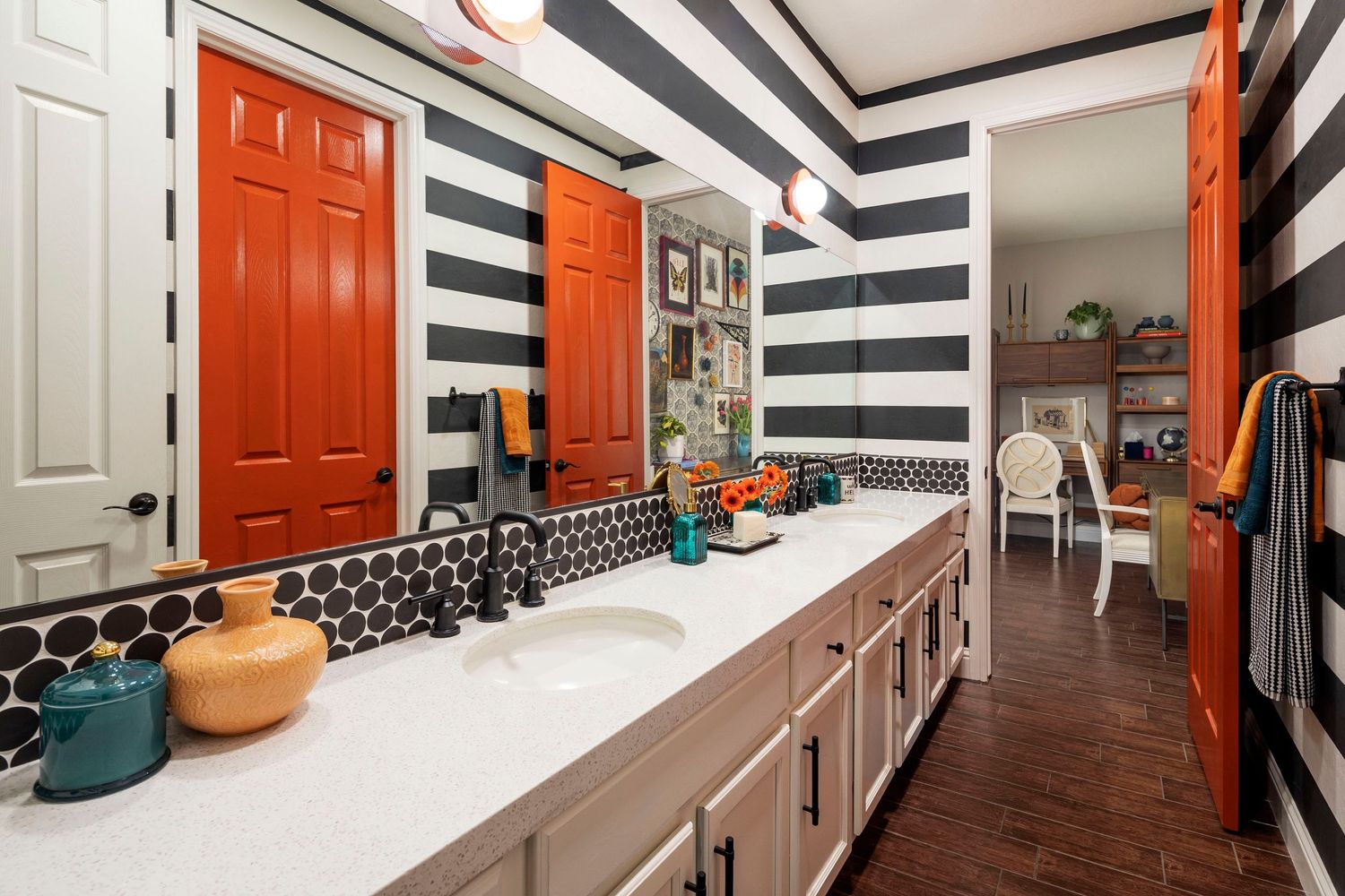 Modern bathroom with bold black and white striped walls and bright orange accents.
