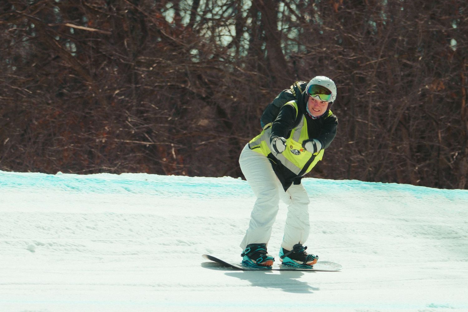 Snowboarder in winter gear carves down a snowy slope.