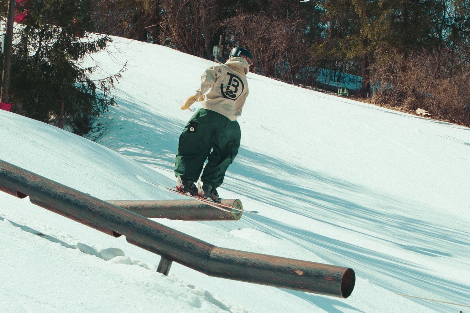 Snowboarder performing a trick while sliding on a rail feature.