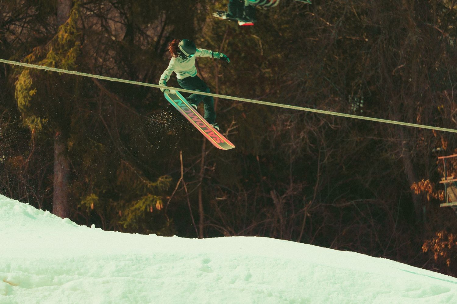 Skier performing aerial jump against dark winter forest background.