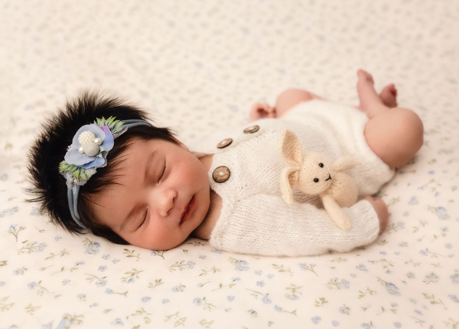 Charlottesville photographer, maternity, baby, and family, newborn girl sleeping on white floral drop with blue accents and holding a bunny.