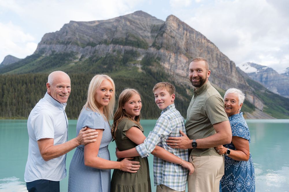 Family of six posing together at Lake Louise with turquoise water and mountain backdrop in Banff, Alberta.