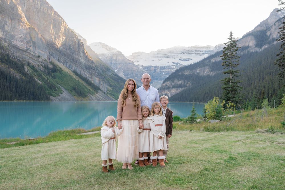 Family of six posing at Lake Louise with turquoise water and Rocky Mountains in the background.