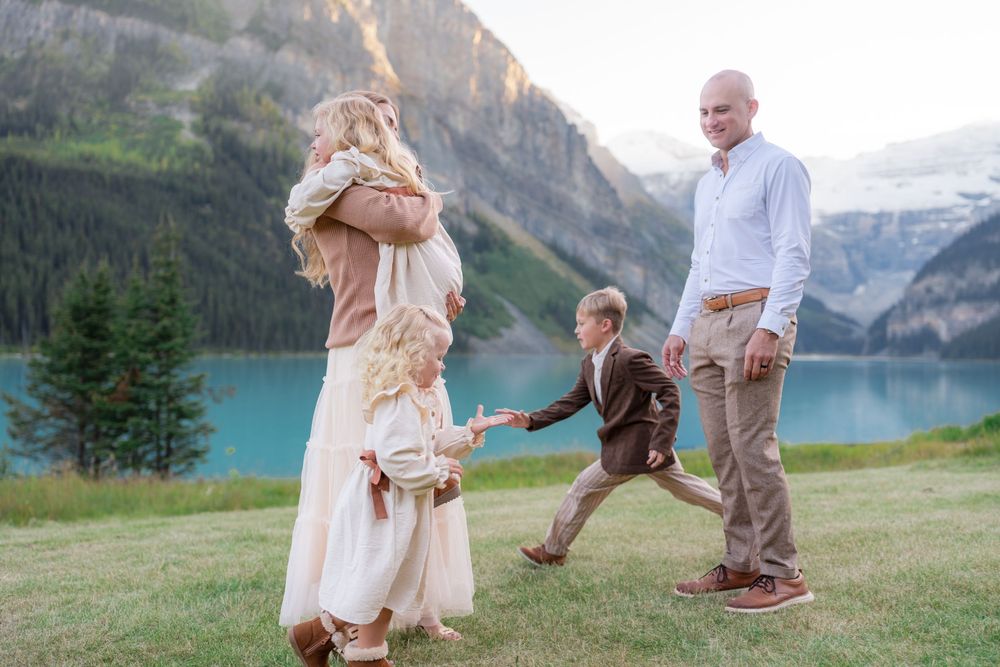 Family posing by turquoise Lake Louise in Banff, mountains backdrop, outdoor elopement photography.