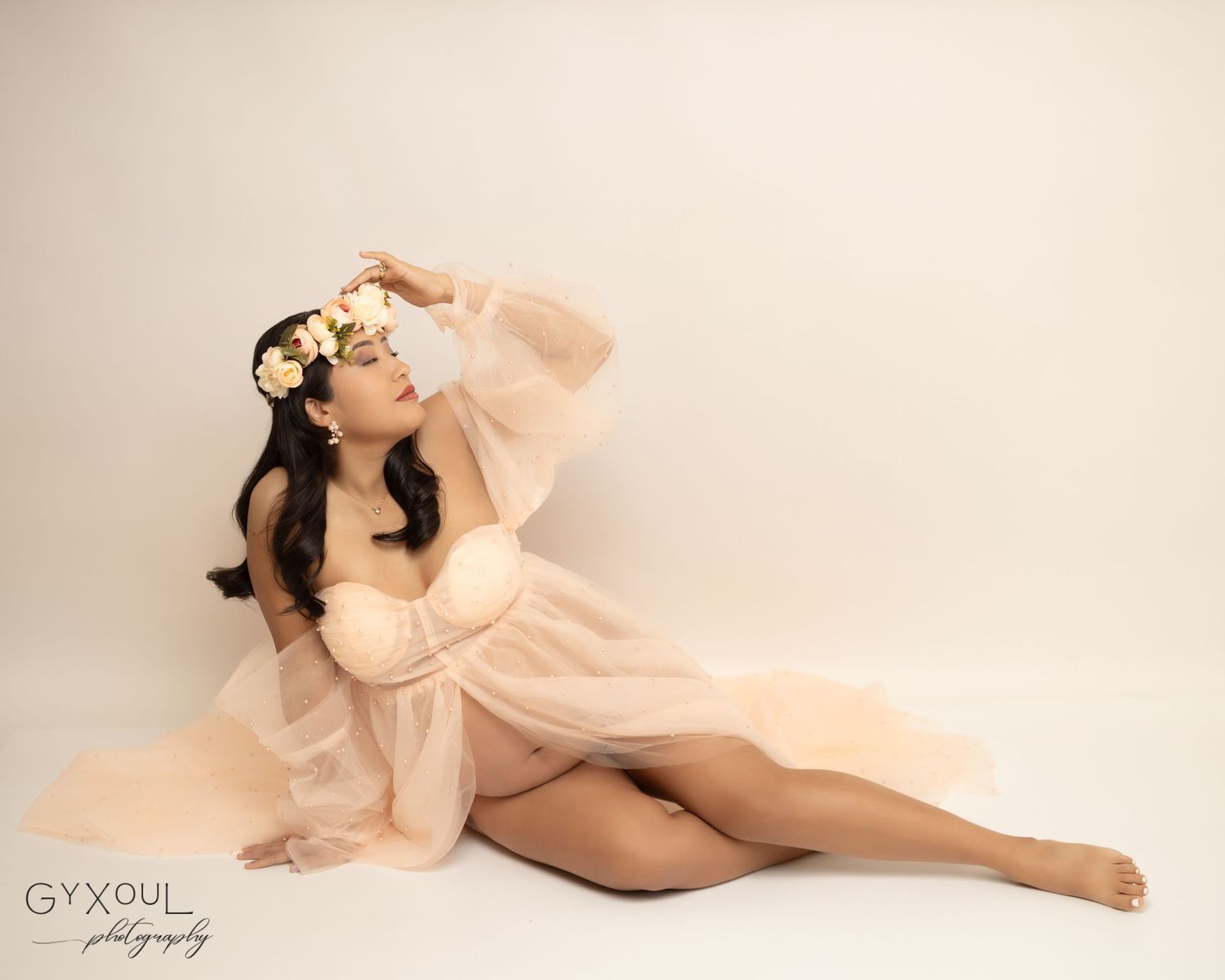 Romantic maternity portrait with subject in sheer dress and floral crown.