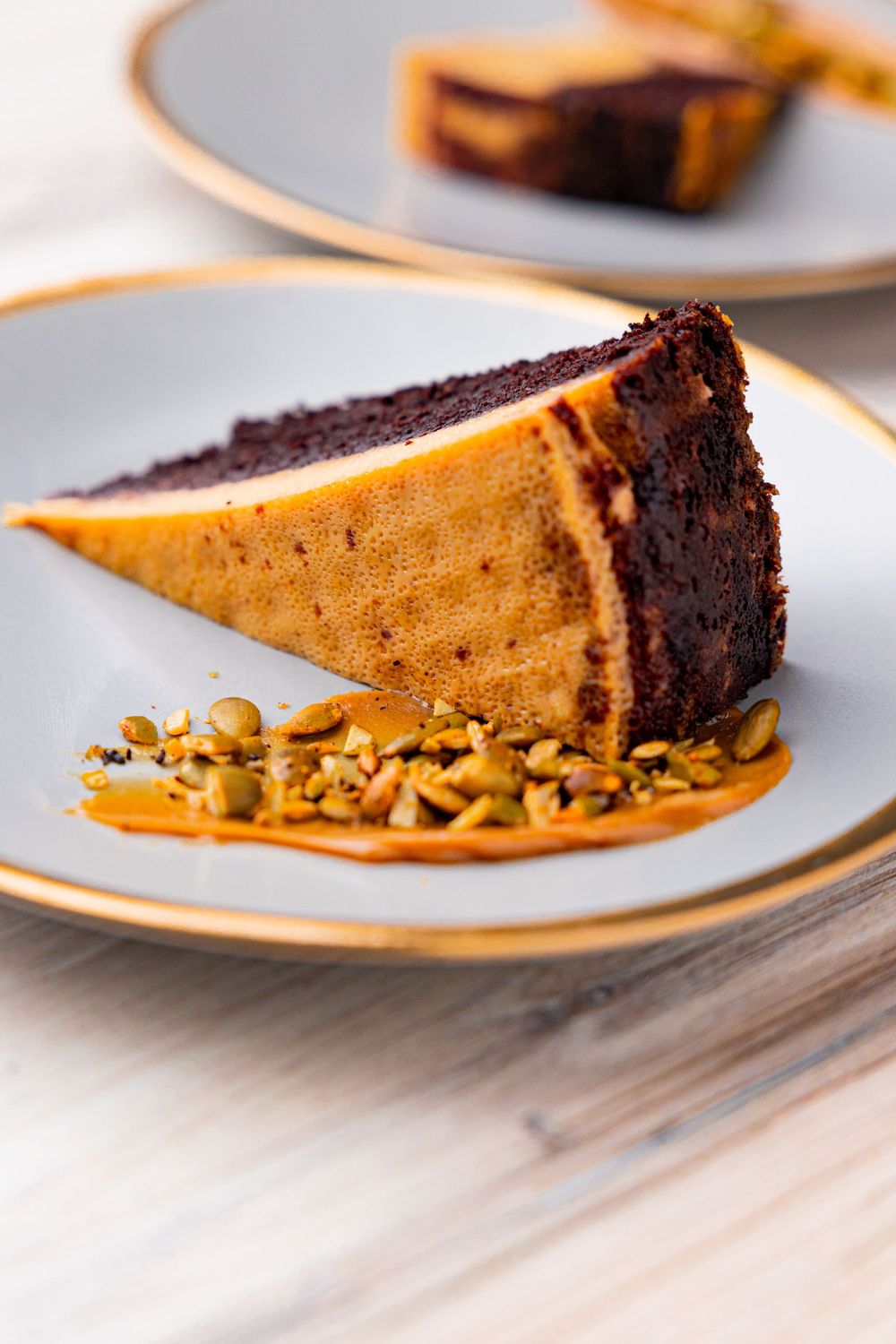 Two-toned chocolate dessert with nuts plated on gold-rimmed dishes.