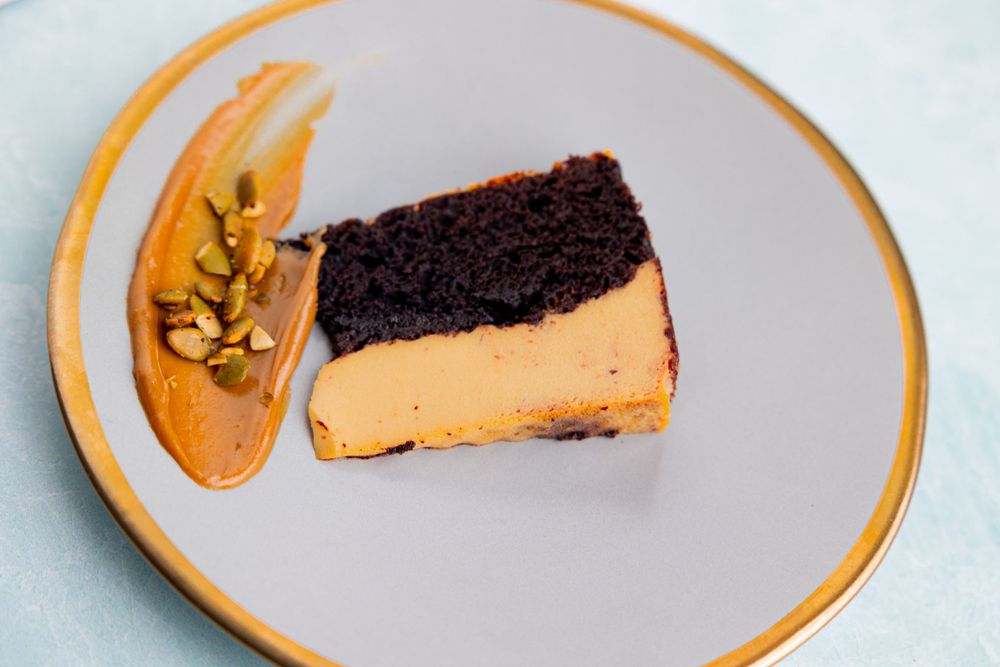 Slices of dessert on white plates with gold trim against light background.