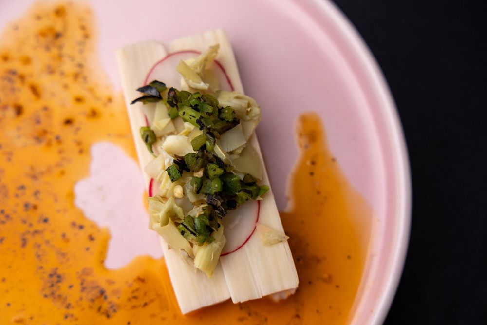 Orange soup with white cheese and fresh herbs in an elegant pink bowl.