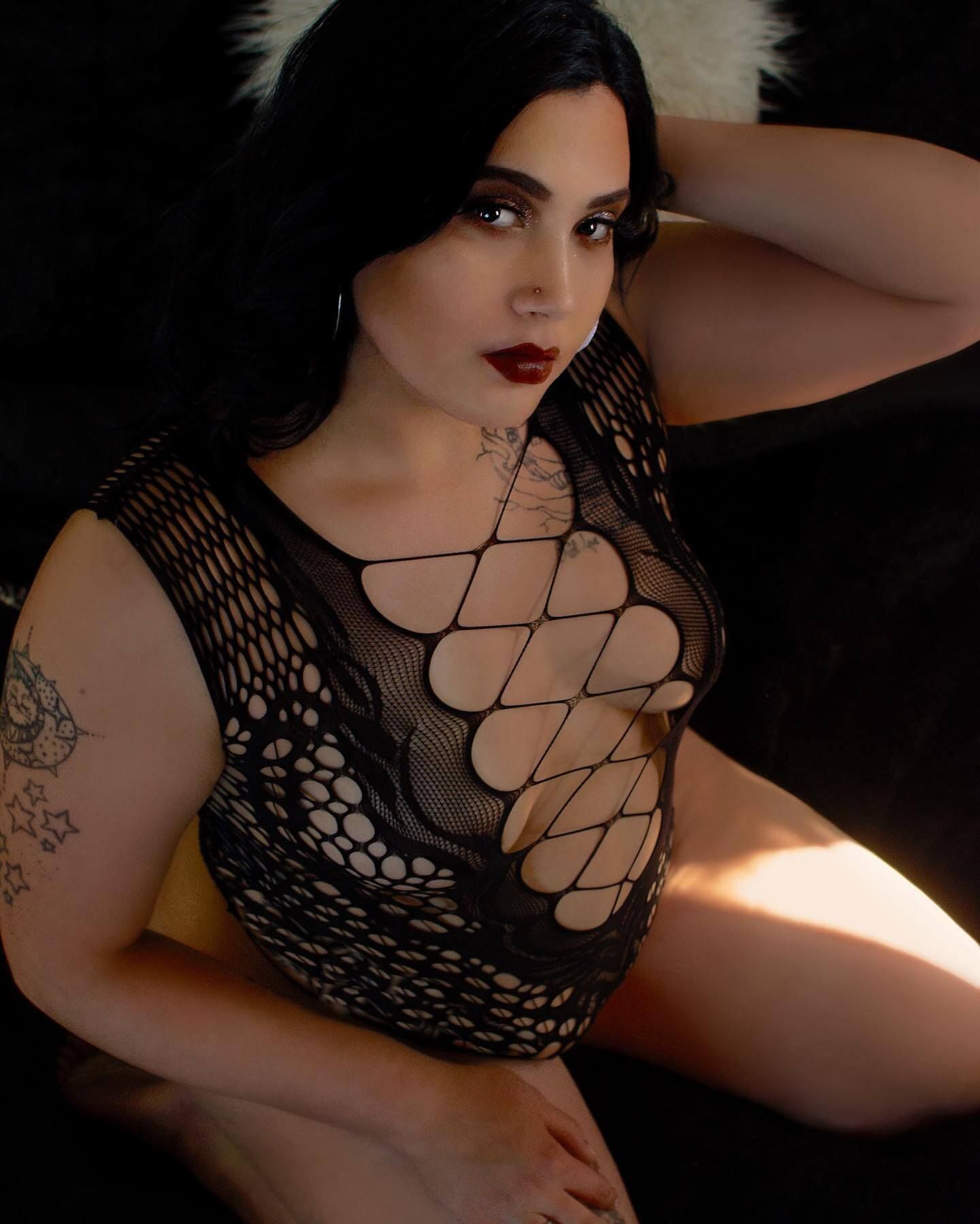 Confident woman in dark mesh lingerie posing on a black backdrop during a Milwaukee boudoir session with Boudoir by Florentina Marie.