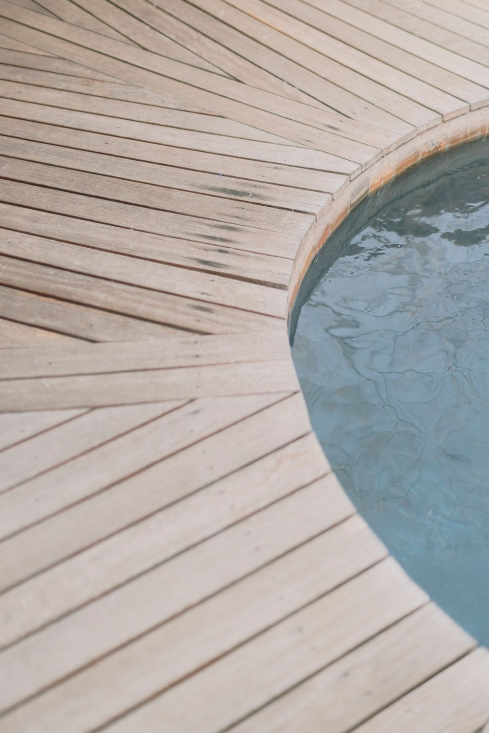 Aerial view of a circular plunge pool with wooden deck surround at a luxury safari lodge.