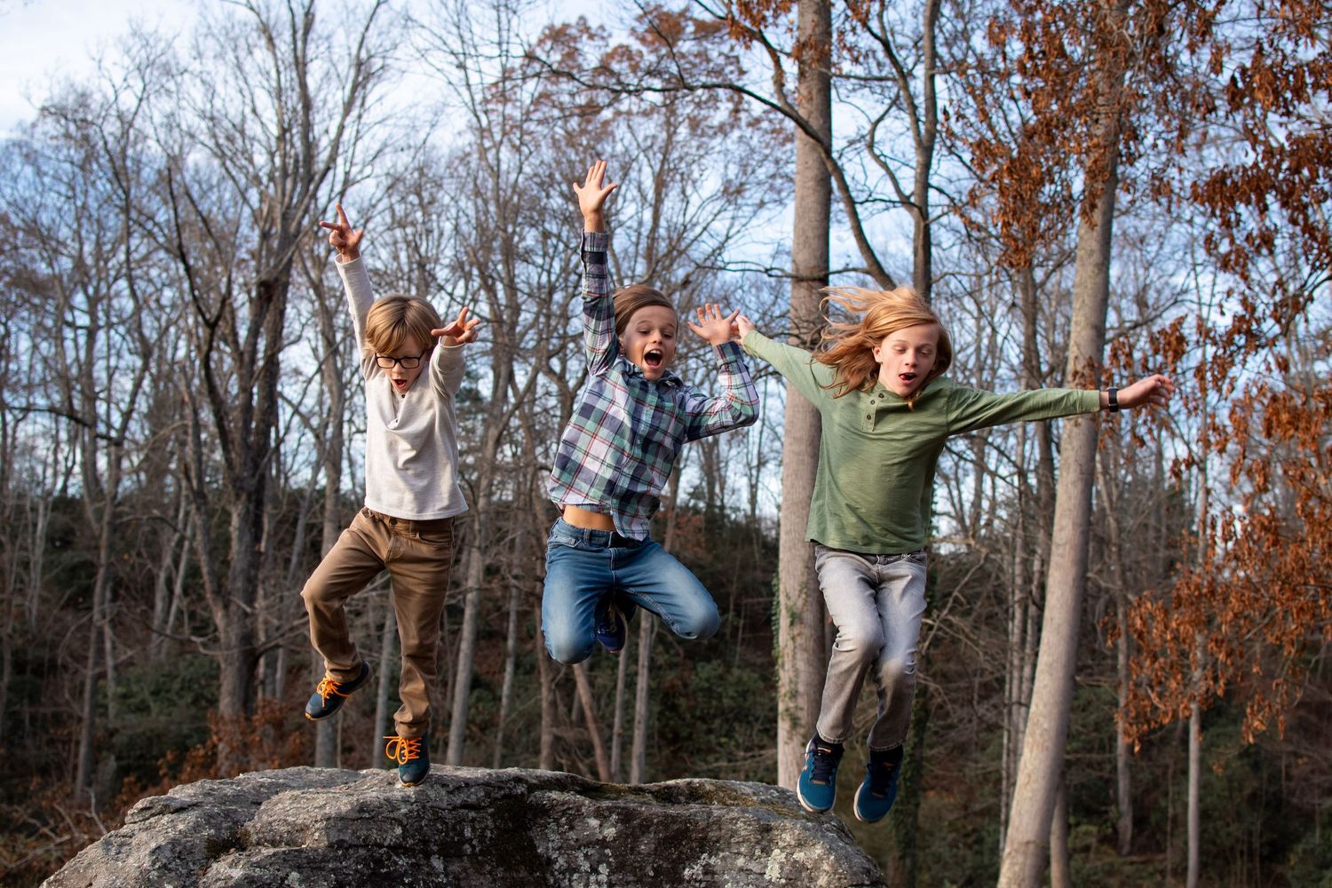 A joyful family shares laughter together while playing in a natural outdoor setting during a black and white photoshoot.