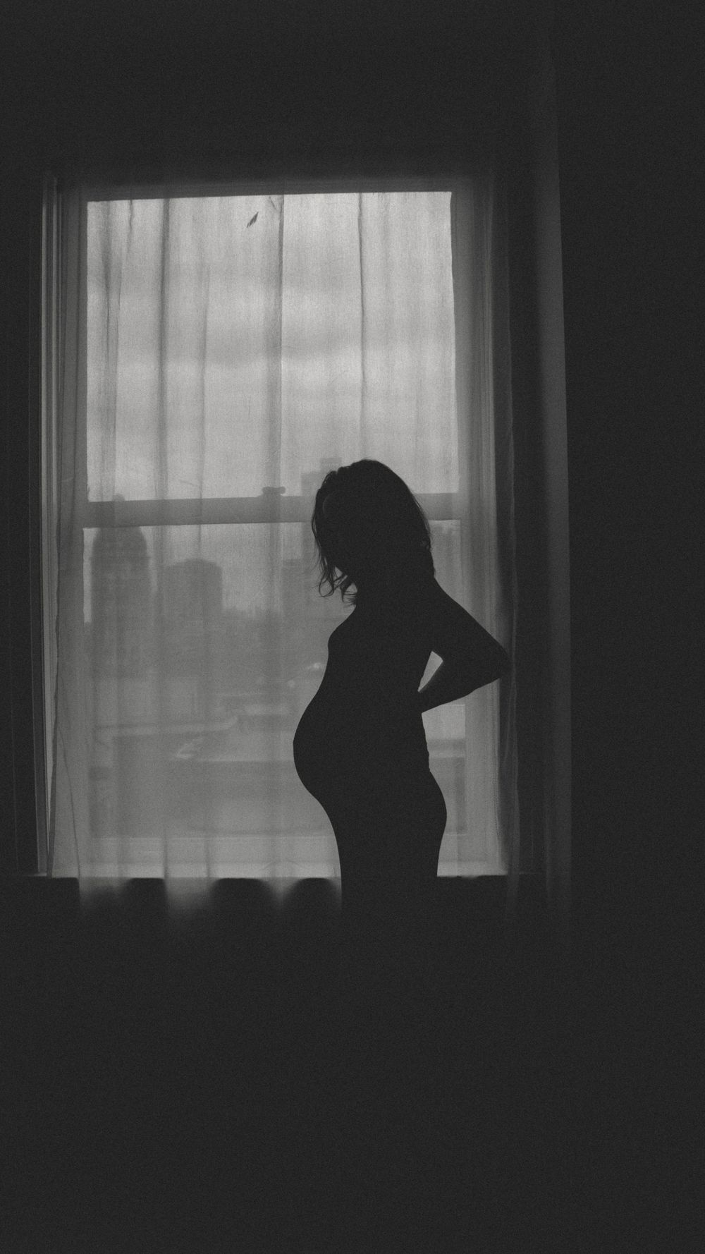 black and white image of an expecting mom's body against the light of the window showing her form during a maternity session in vancouver.